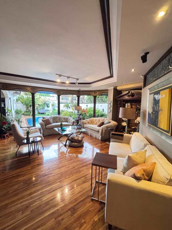 Large living room with hardwood floors, big windows overlooking garden and pool in El Carmen Panama