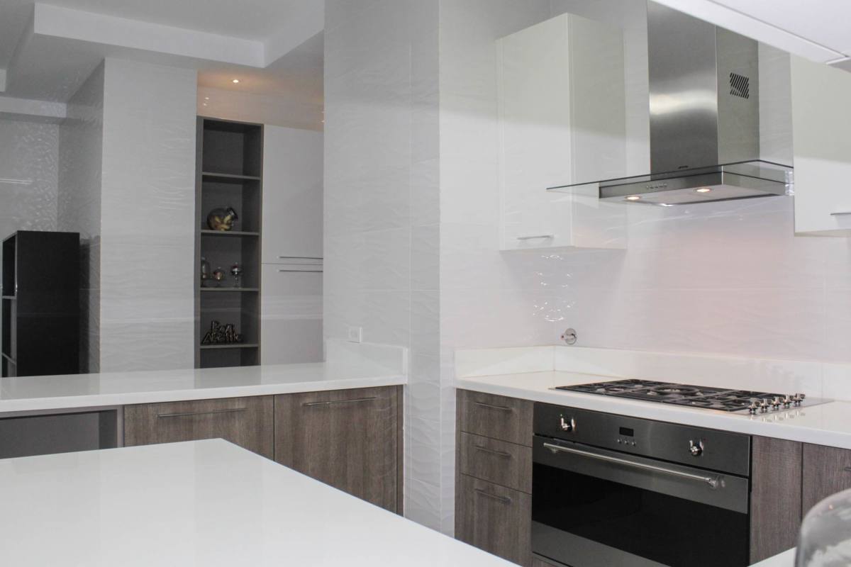 Sleek kitchen with built-in gas stove white countertops stainless hood Ocean House Santa Maria