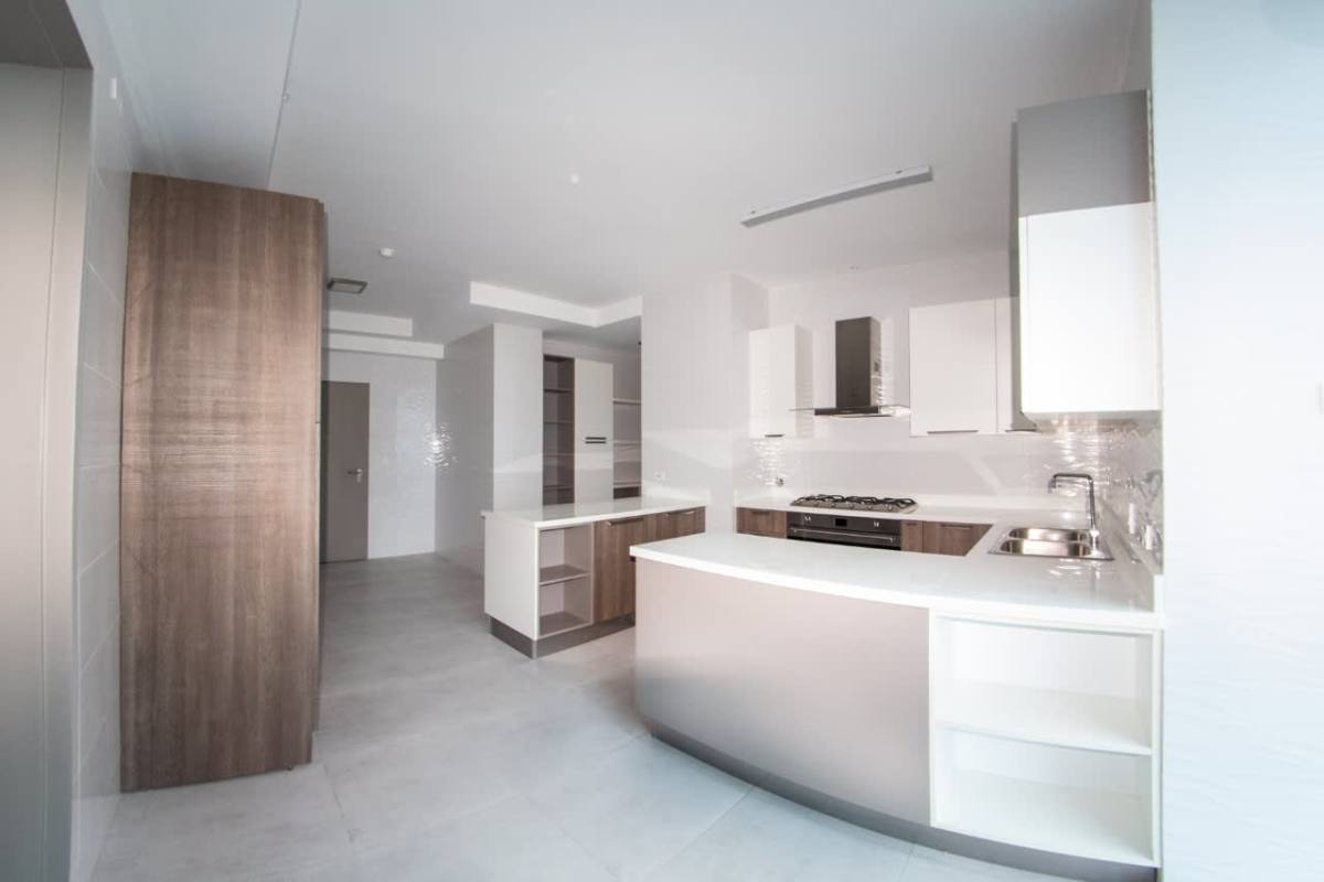 Modern kitchen with wood cabinetry, island counter PH Oceana Residences Costa del Este Panama