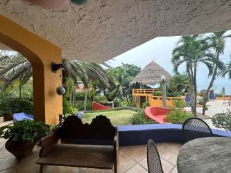 Colorful tropical garden patio with palapa roof, oceanfront luxury villa Punta Roca Panama