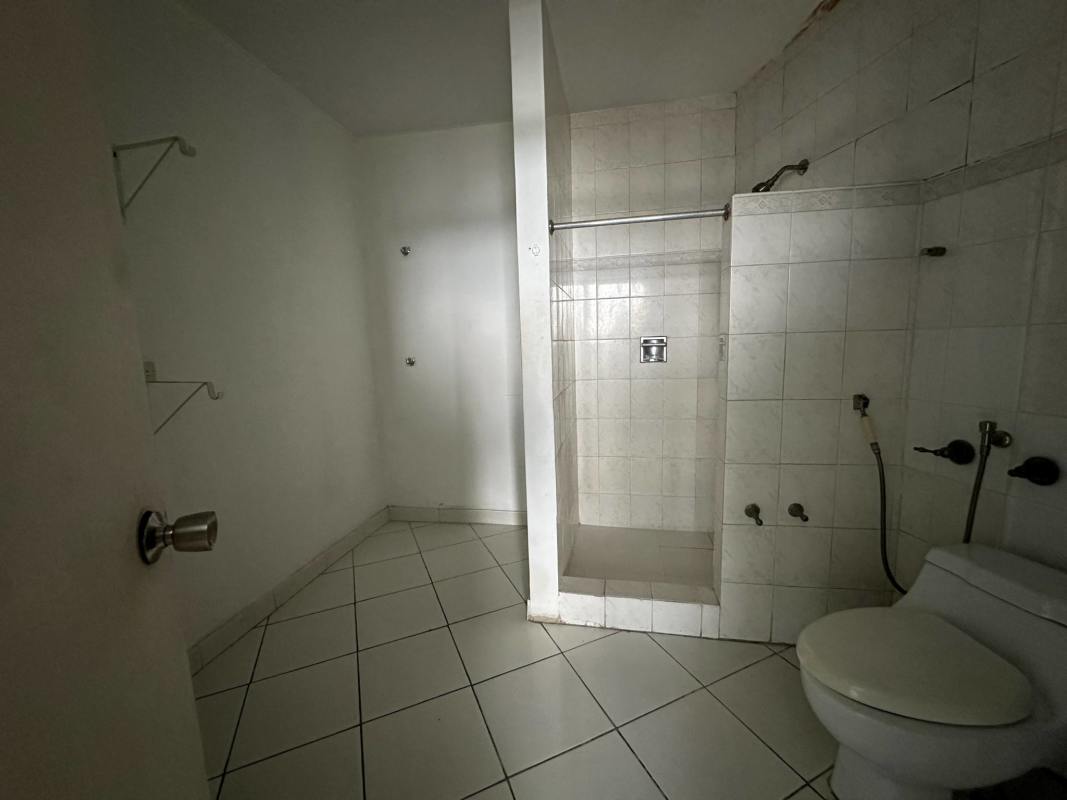 Simple white ceramic tiled bathroom with walk-in shower in Betania Panama condo