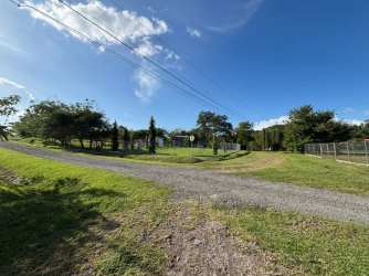 Grassy countryside lot with fence and gravel road access Hacienda La Florenciana San Carlos Panama