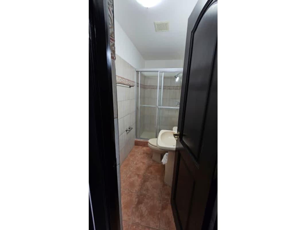 Bathroom with glass shower enclosure, ceramic tiles, pedestal sink in house Brisas del Golf Panama