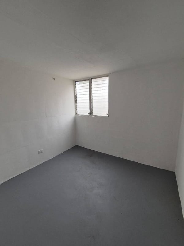 Empty small bedroom with louvered window, white walls, gray flooring Villa Lorena Panama City