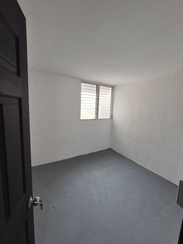 Empty small bedroom with white walls louvered window gray flooring Villa Lorena Panama