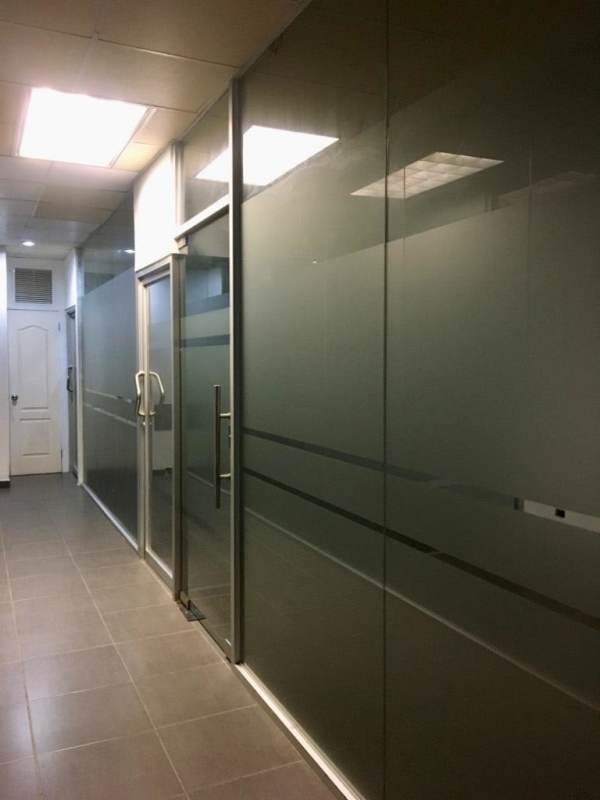 Commercial hallway with frosted glass partitions, tiled floor, and fluorescent lighting in Plaza Clayton Panama