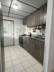 Spacious kitchen with wooden cabinetry, tiled floor, gas stove, metal sink in Lomas de Mastranto house