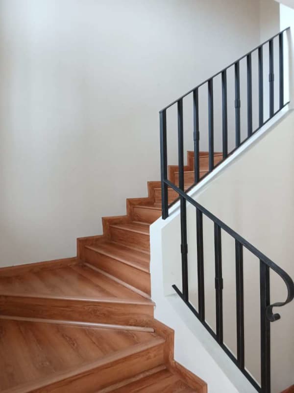 Interior staircase with wood steps and black railing in modern two-story house Versalles Panama