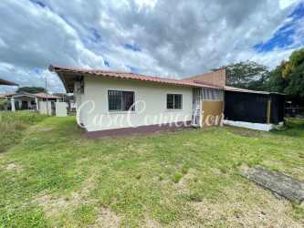 Covered parking area with garden and fence in front of duplex rental house David Panama