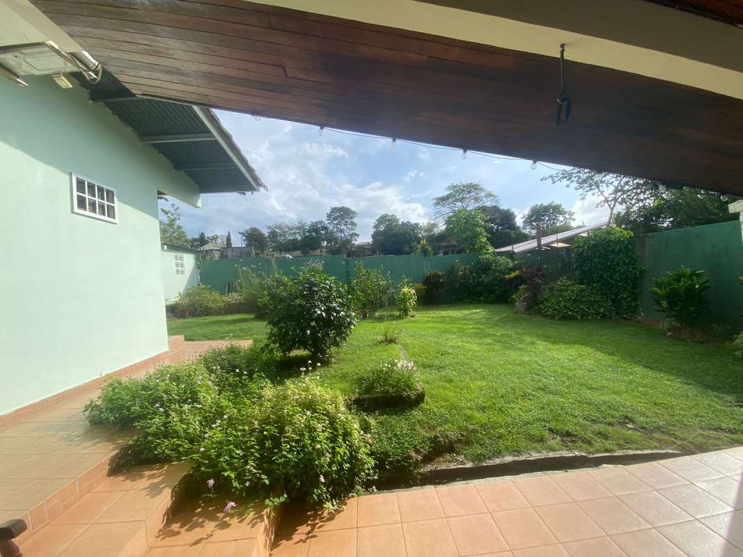 Spacious backyard with grass lawn, garden beds, and tiled patio area Las Cumbres Panama