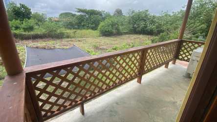 Two-story yellow house with balcony and fenced yard Playa Gorgona Panama investment property