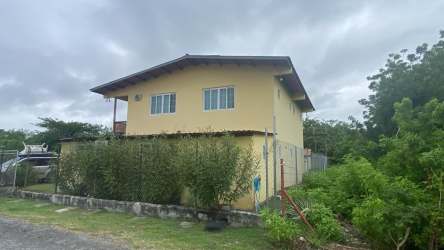 Two-story yellow residential house with balconies and front garden Playa Gorgona Panama