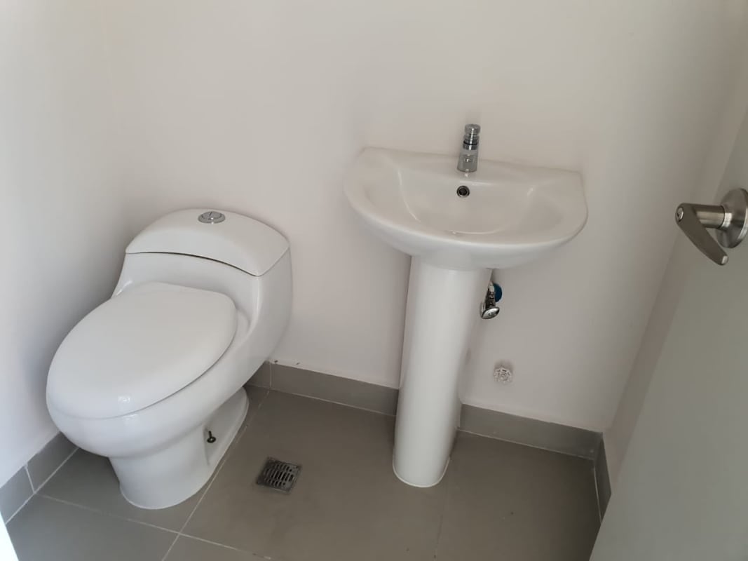 Small minimalist bathroom with white toilet pedestal sink ceramic flooring in Costa del Este office Panama