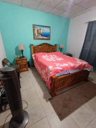 Bedroom with wooden bed, turquoise wall, tile floors Penonomé Panama