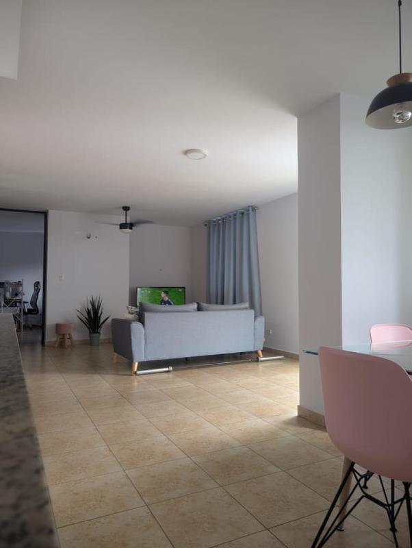 Dining area with glass table pink chairs open kitchen pass-through PH Torres de Transistmica Panama