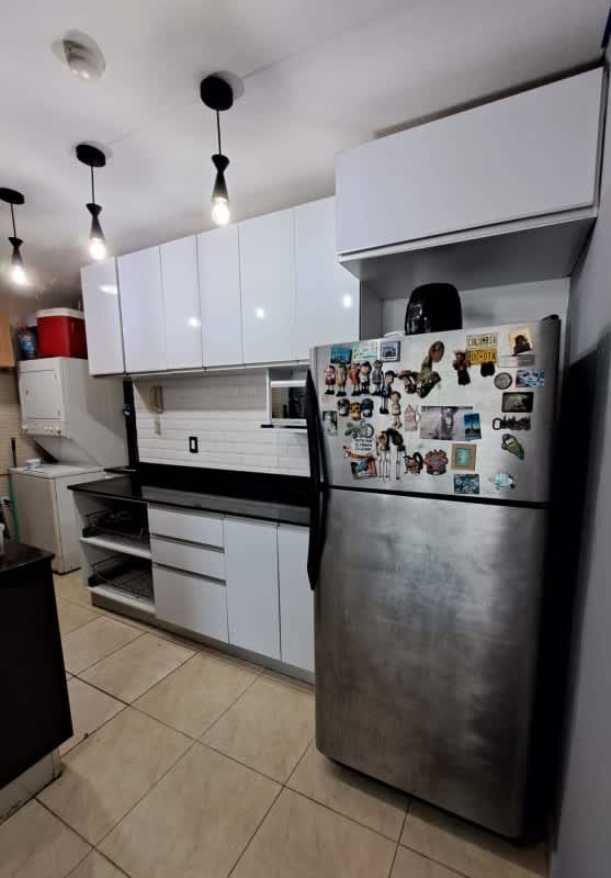 Kitchen with white cabinets, stainless fridge, black countertop and pendant lights PH Albrook Residence Panama City