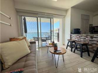 Furnished living room with large glass doors and ocean view balcony Playa Caracol