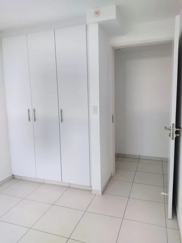 Modern bathroom with tiled walls, vanity sink, shower curtain in El Crisol Towers apartment