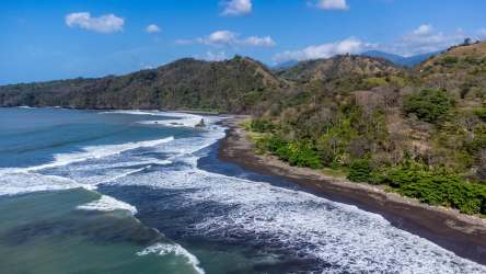 Aerial coastal image with surf waves rocky cliffs and forested land Cambutal Panama