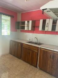 Kitchen with coral pink walls, wood cabinets, backsplash tiles in La Enea Guararé Los Santos Panama