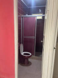 Bathroom with burgundy tiles, glass shower enclosure, and toilet in La Enea Guararé Los Santos Panama