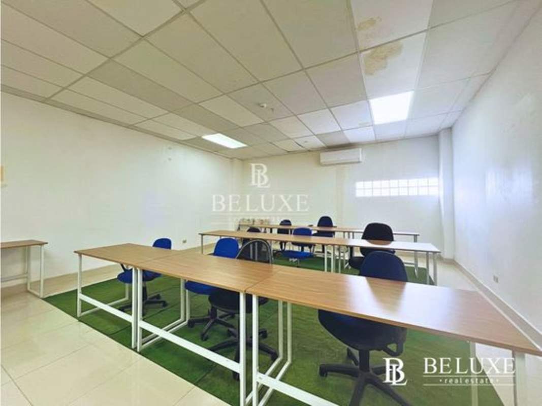 Row of desks and office chairs with drop ceiling, glass divider in PH Torre USB El Carmen