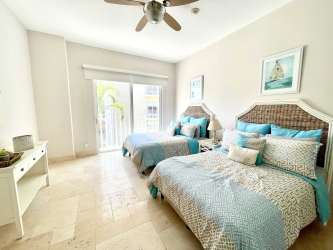 Spacious bathroom with double sinks, large mirrors, glass shower in luxury beachfront condo