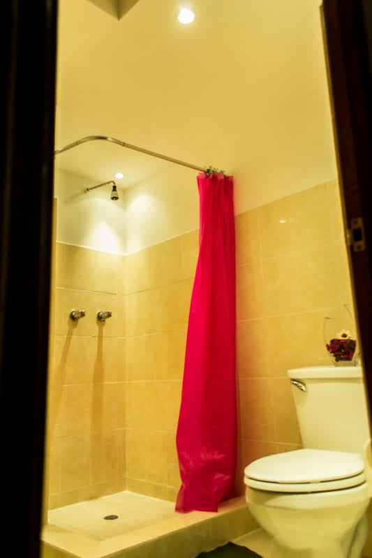 Bathroom with beige tiles, pink curtain, toilet and sink in PH Roca Park Panama