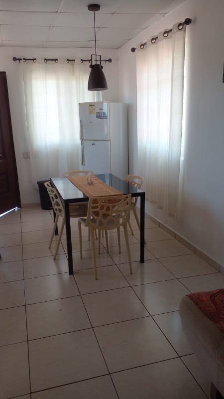 Compact living and dining area with sofa, TV and tile floors in Villa Lucre apartment