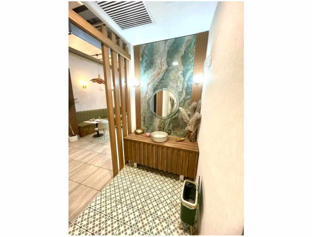 Stylish bathroom with stone wall, round mirror, vessel sink in Casco Viejo restaurant Panama