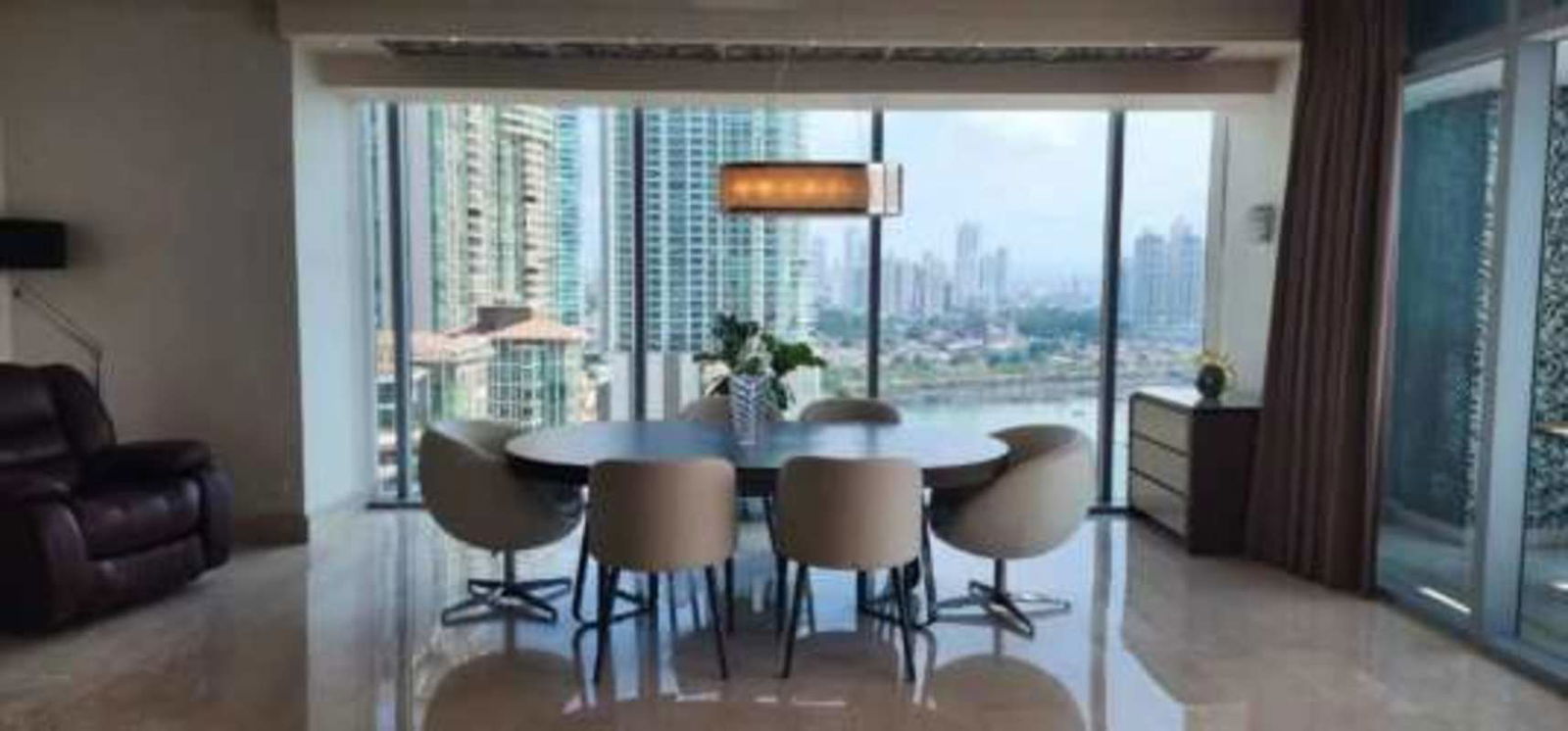 Modern dining room with floor-to-ceiling windows overlooking city skyline and Pacific Ocean at Grand Tower Punta Pacifica