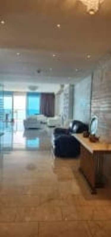 Spacious living room with ocean view, marble floors and stone accent wall at Grand Tower Punta Pacifica