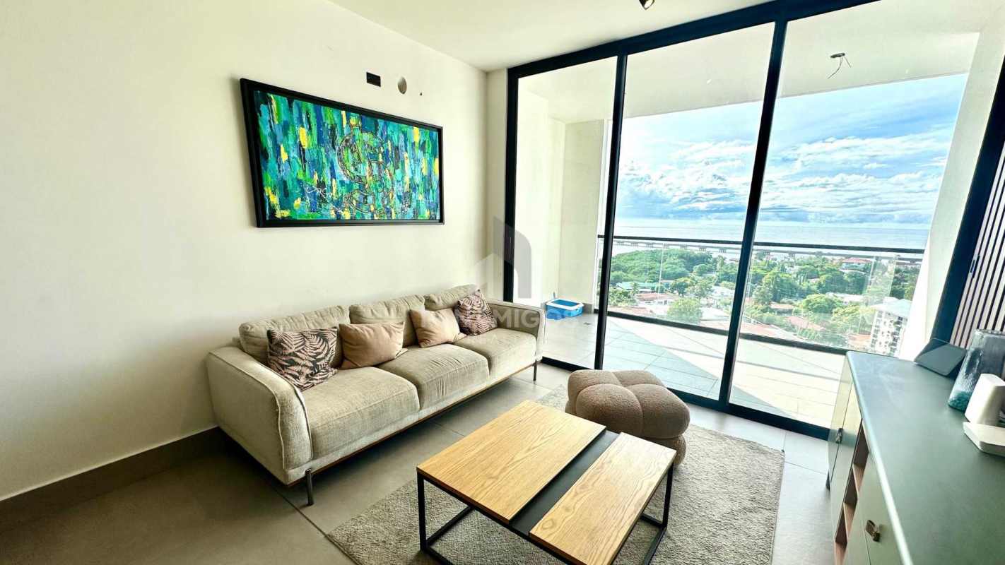 Spacious living room with large glass doors leading to balcony with panoramic ocean and city views in Coco del Mar Panama
