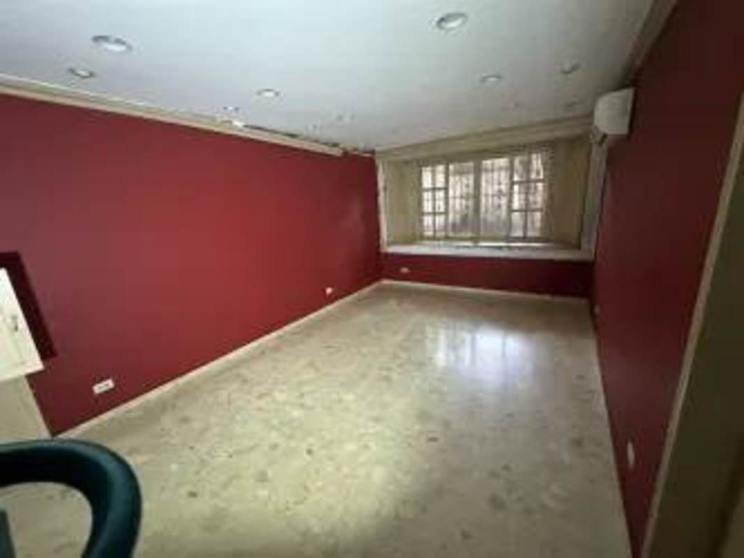 Spacious room with large window, marble floors, deep red accent wall in Obarrio rental house Panama