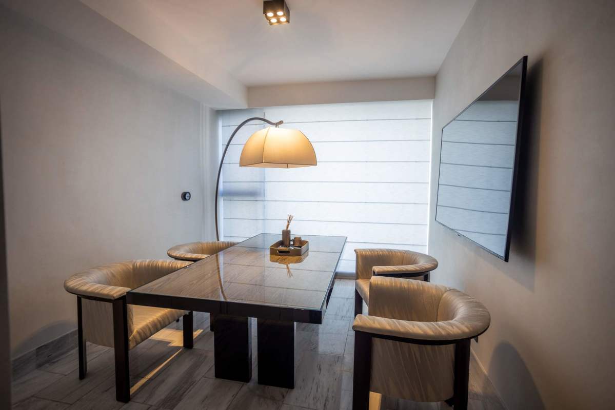 Minimalist dining room with glass table and large TV in Nuovo by Armani Casa Panama
