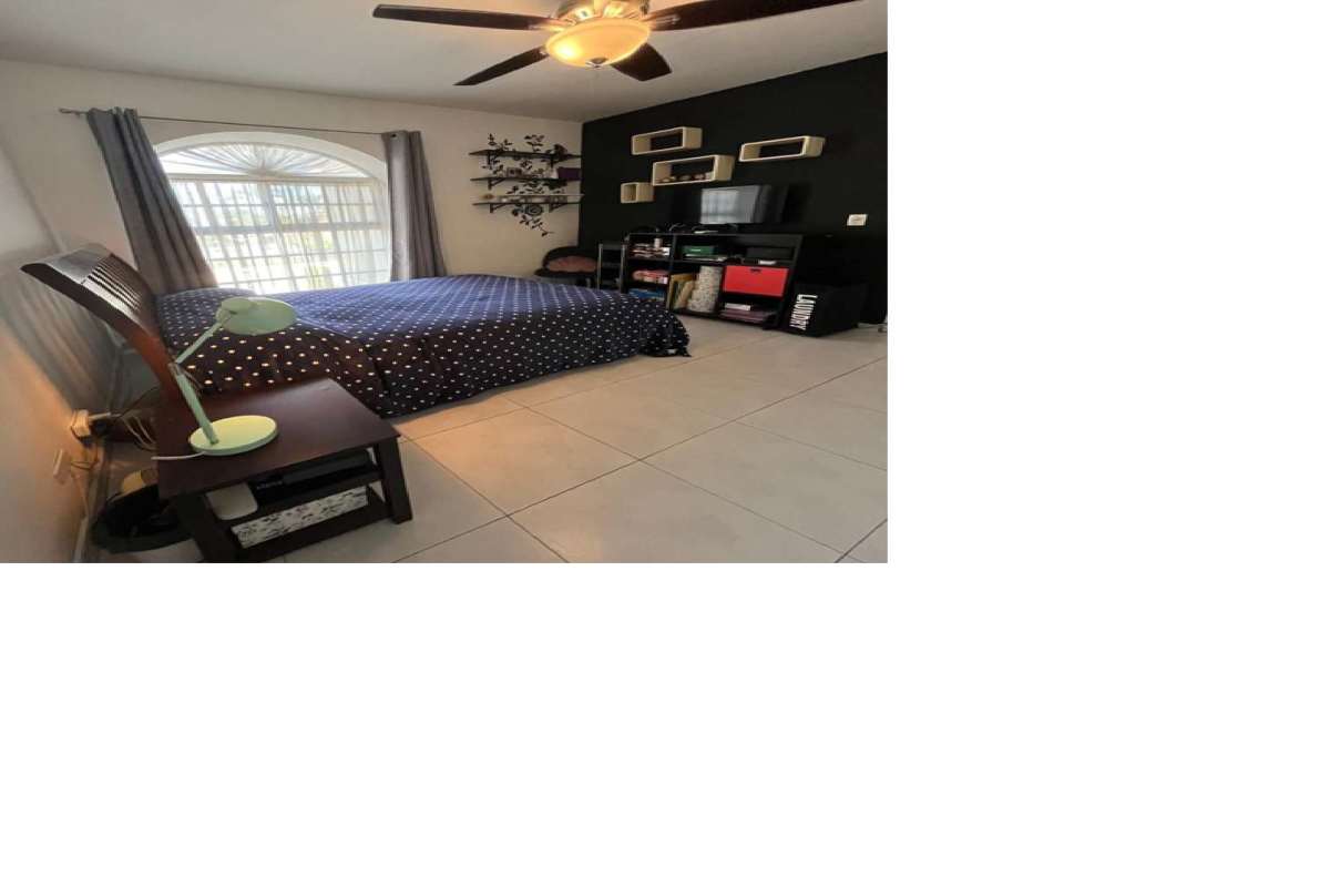 Bedroom with striped accent wall, workspace and AC in Villa de las Fuentes Panama