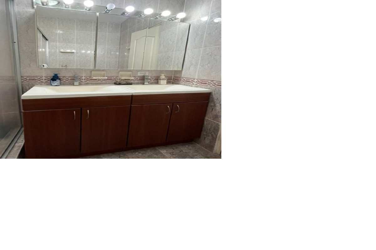 Traditional bathroom with double sink, large mirror, tile walls in Villa de las Fuentes Panama