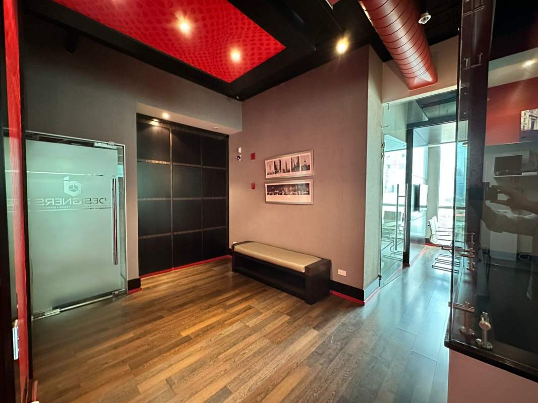Lobby area with glass door, wood floor, red ceiling accents at PH BICSA Tower office for sale Panama