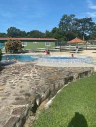 Pool facility next to flat green areas and playground inside Cabuya Gardens gated community Panama Oeste Panama