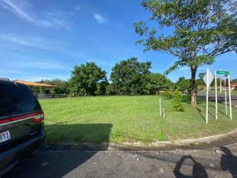 Corner grassy lot with paved street access, utilities, and rural countryside views inside Cabuya Gardens Chame Panama