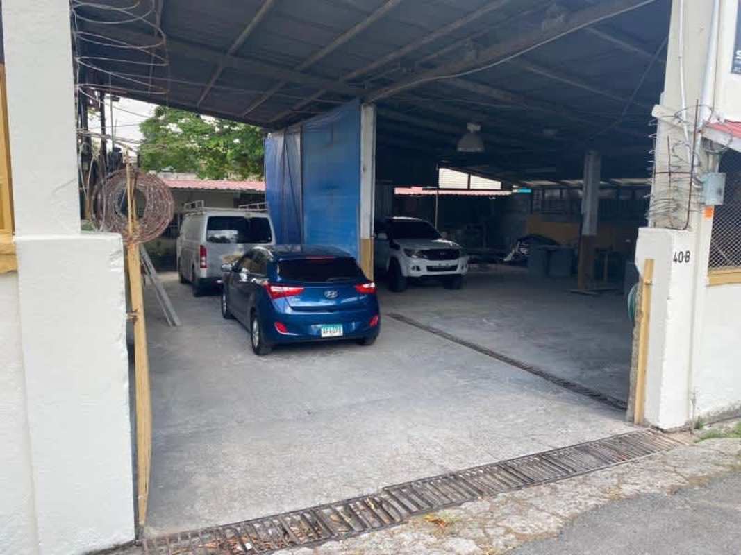 Covered garage space with metal roof and multiple parked cars inside barbed fence Don Bosco Panama