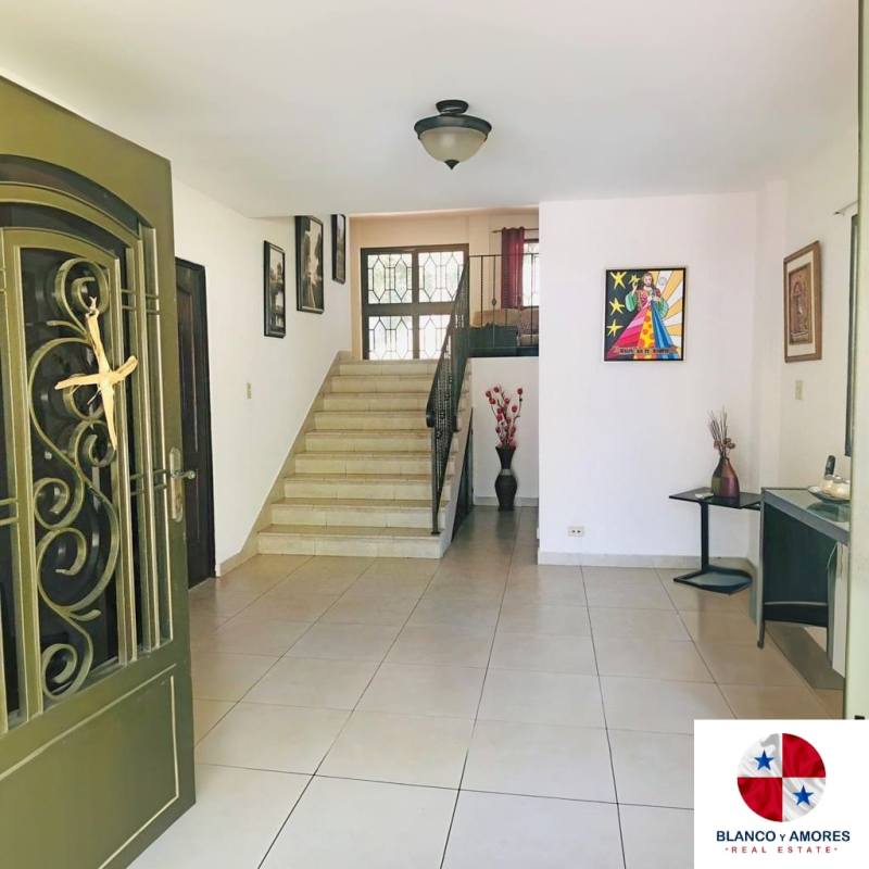 Spacious foyer with decorative metal entrance door, stairs, art and tile floor in Panama rental