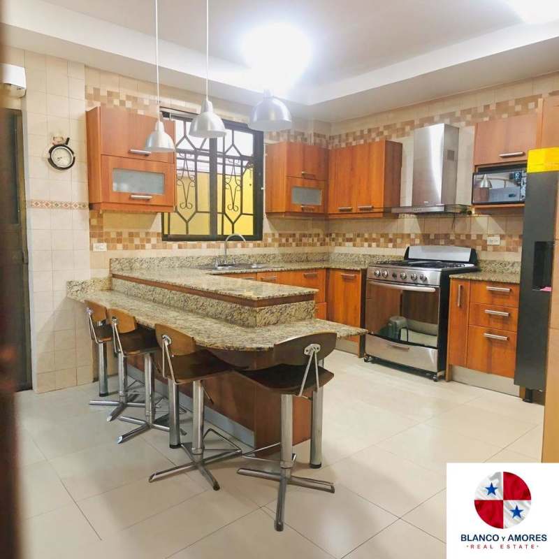 Modern kitchen with granite counter, wood cabinets, tile backsplash, stove and pendant lights in Ancon Panama
