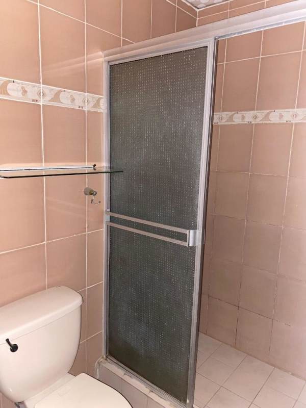 Bathroom interior with glass shower doors, beige tiles, and white toilet in El Crisol Panama