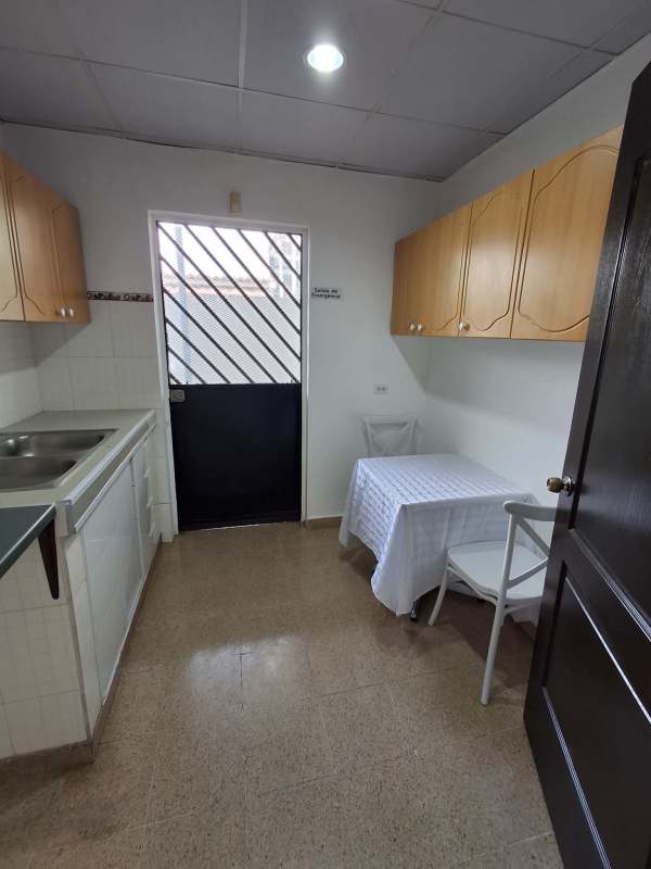 Basic kitchen with wood cabinets and dining area in commercial house Panama City