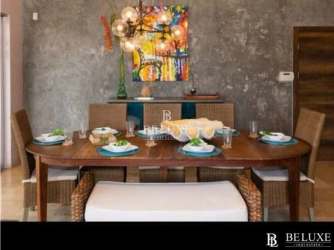 Dining area with wooden table, woven chairs, modern decor and garden views in Punta Barco villa Panama