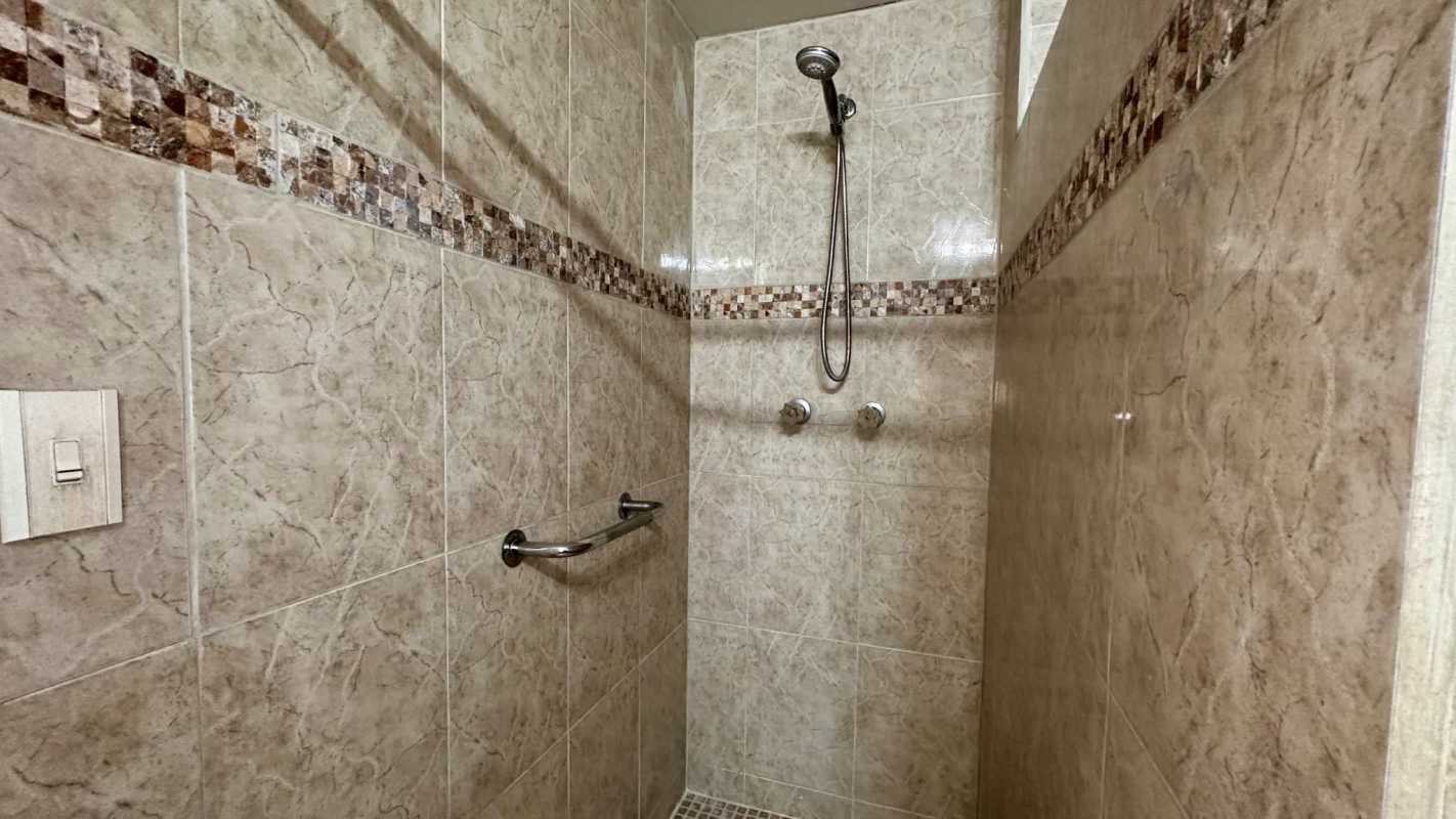 Modern bathroom with wood vanity, wall mirror, shower and soap dispenser Las Fuentes Panama