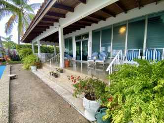 Mid-century modern covered patio with outdoor seating, pool, and tropical garden in Coronado Panama.