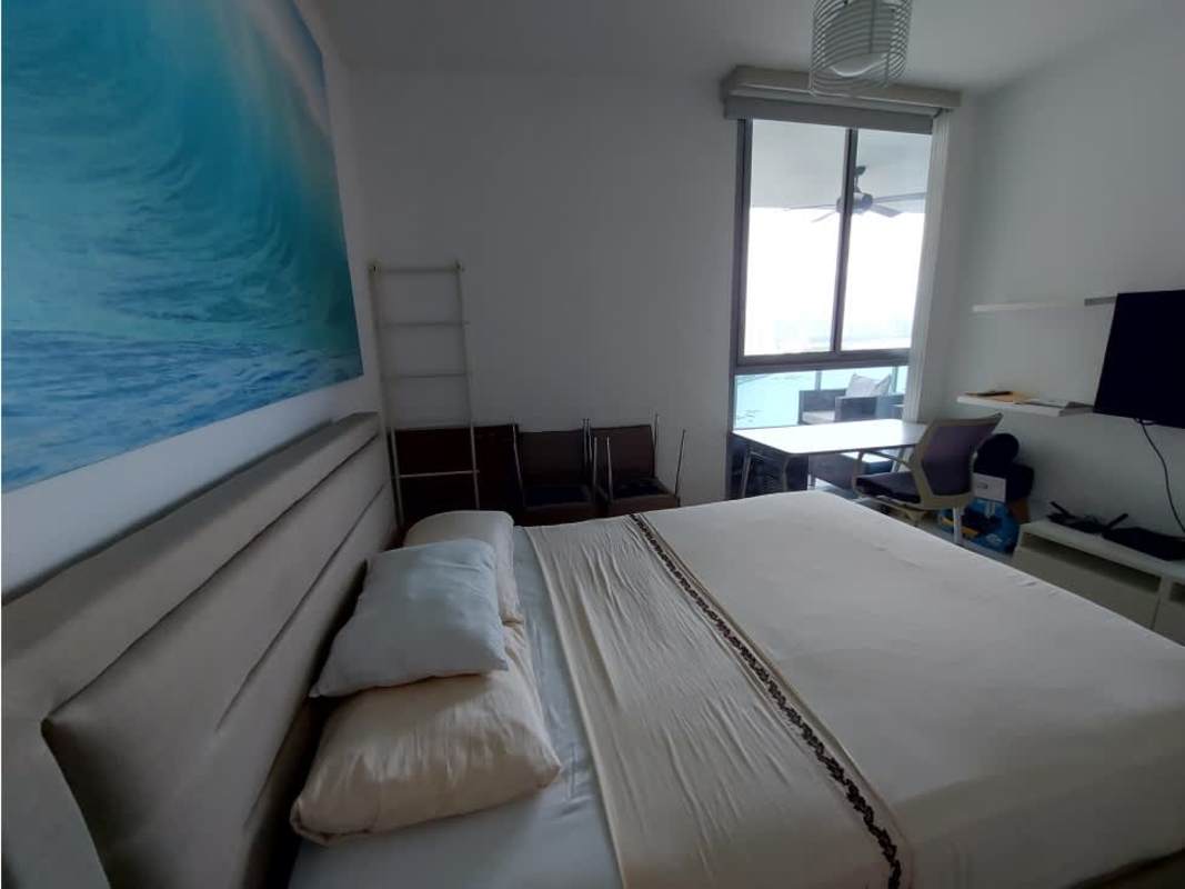 Living room with TV console and city/ocean view balcony PH Grand Tower Panama City