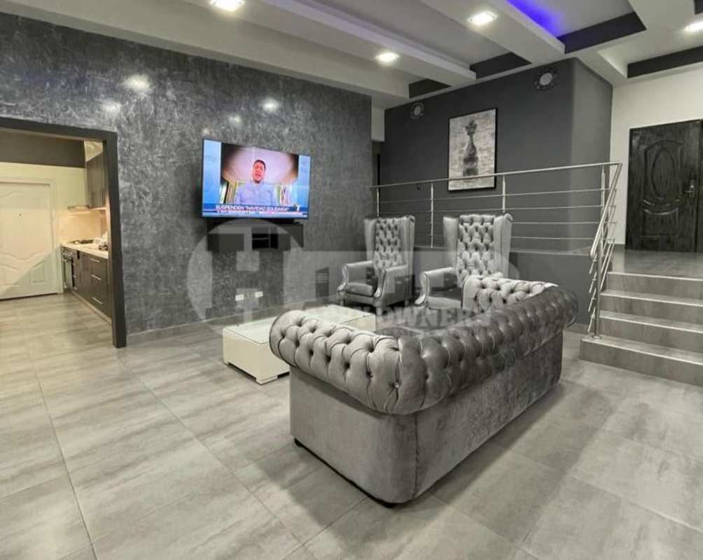 Open plan living area with marble accent wall, gray tufted sectional, TV and modern design in Condado del Rey Panama